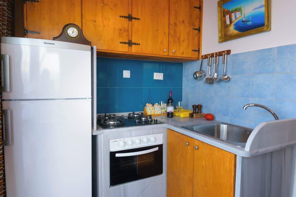 A compact kitchen with a refrigerator, stove, oven, and sink.
