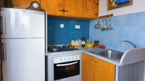 Eine kleine Küche mit Kühlschrank, Herd, Backofen und Spüle.