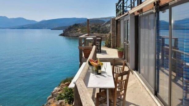 A balcony with a table and chairs overlooking a body of water and mountains. - Seaside Ntounas Apartments - Ammoudara Triple Gem (Agios Nikolaos)