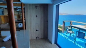 A modern room with a large window, a wooden floor, and a view of the sea. - Seaside Ntounas Apartments - Ammoudara Triple Gem (Agios Nikolaos)