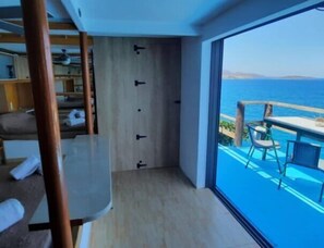 Ein modernes Zimmer mit großem Fenster, Holzboden und Meerblick.