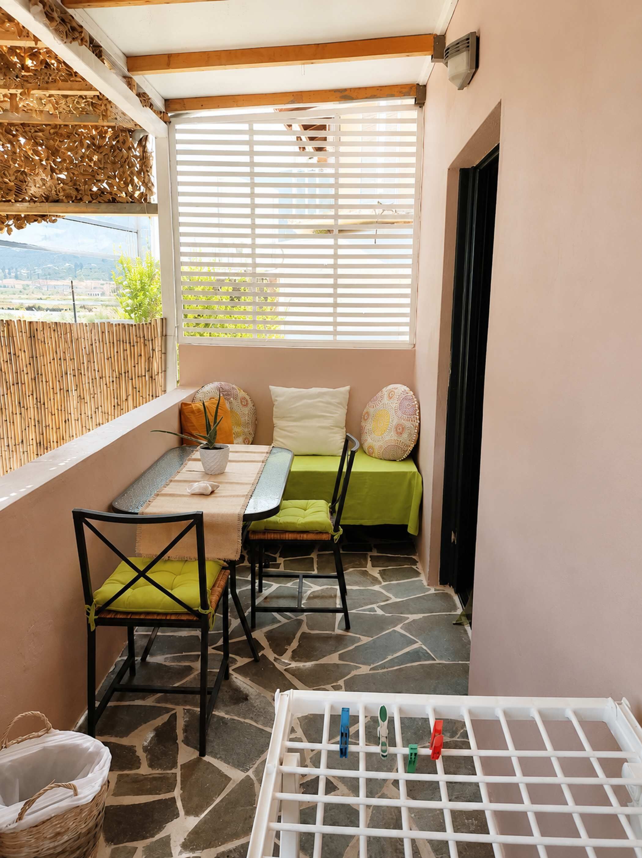 A balcony with a table, chairs, and a drying rack.