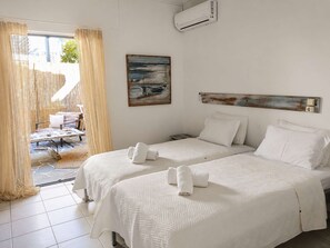 Ein Hotelzimmer mit zwei Betten, einem Gemälde, einer Klimaanlage und Blick ins Freie.