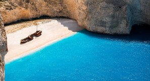 Ein Strand mit klarem, blauem Wasser, einem Sandstrand und einem Boot.