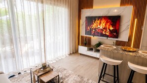 Ein modernes Wohnzimmer mit Fernseher, einer Couch, einem Couchtisch und einer Bar.