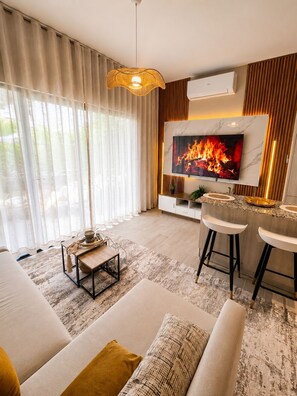 Een moderne woonkamer met een televisie, bank, salontafel en een barhoek.