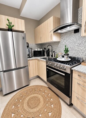 Een moderne keuken met roestvrijstalen apparatuur, houten kastjes en een granieten aanrecht.