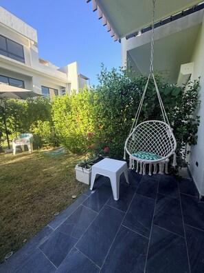 Ein Patio mit Hängesessel, kleinem Tisch und Topfpflanzen.