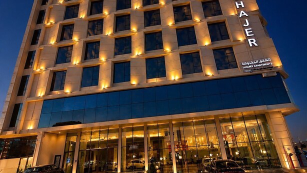 Ett hotell med flera våningar, upplysta fönster och en fasad av glas.