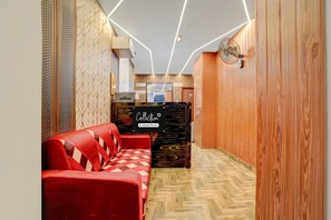 A reception area with a red sofa, a wooden reception desk, and a patterned wall.