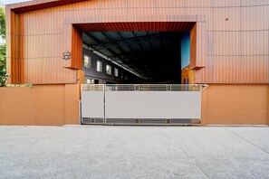 A large industrial building with a metal gate, a covered entrance, and a visible interior with windows and a staircase. - Super Collection O Kovur (Chennai)