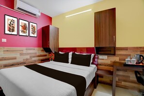A hotel room with a bed, a desk with a kettle, and a wall-mounted air conditioner. - Super Collection O Kovur (Chennai)