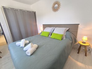 A neatly made bed with pillows, a bedside lamp, and a curtain. - L'OLivier de Romolea 4personnes/jardin classée 3 étoiles (Roumoules)