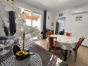 Ein Essbereich mit einem Tisch für zwei Personen, einem Stuhl und einer Blumenvase.
