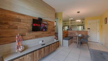 Una cocina moderna con una pared de acento de madera, un televisor integrado y una zona de comedor con mesa y sillas.