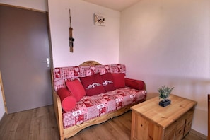 Ein Zimmer mit einer Holzsofa, einem kleinen Holztisch und einer Tür.