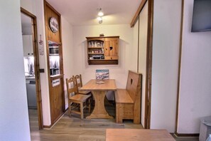 Ein Holztisch mit Stühlen, eine Holzkommode mit Glaswaren und eine Uhr an der Wand.
