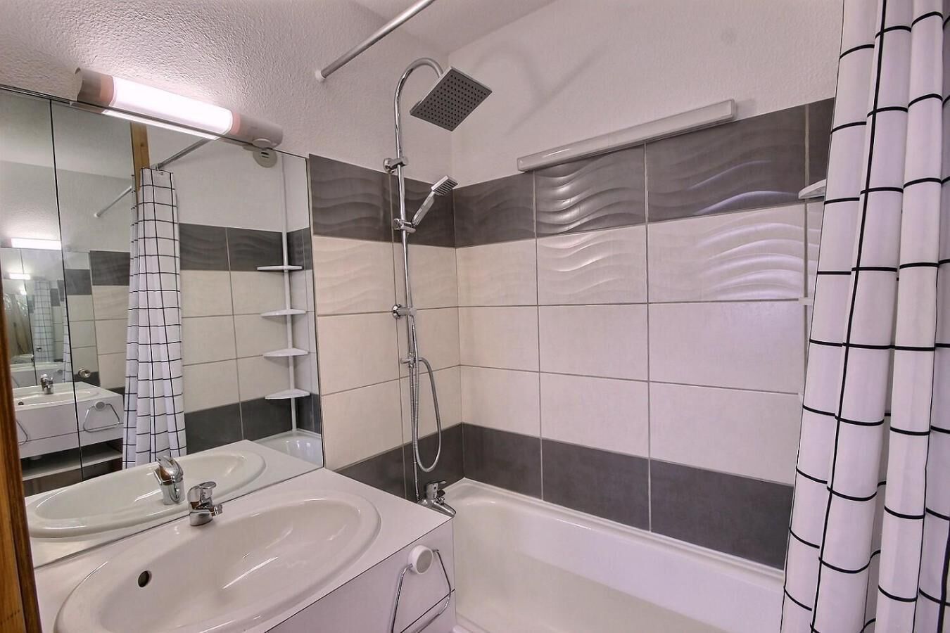 Une salle de bain avec une douche, deux lavabos, un miroir et une baignoire.
