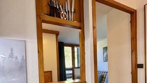 Un intérieur en bois comprenant un coin cuisine, un miroir et une chambre à coucher visible à travers une porte ouverte.