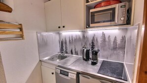 Une petite cuisine équipée d’un évier en acier inoxydable, d’un four à micro-ondes et d’une machine à café.