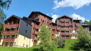 Un hôtel à plusieurs étages, doté de balcons, d’un toit plat et d’une façade où se mêlent différents matériaux de construction.