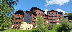 Ein mehrstöckiges Hotel mit Balkonen, flachem Dach und einer Mischung aus Baumaterialien.