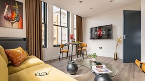 A modern living room with a sofa, coffee table, and a dining area with chairs.