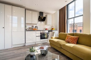 Una cocina moderna con armarios blancos, horno empotrado y ventana con vistas a edificios.