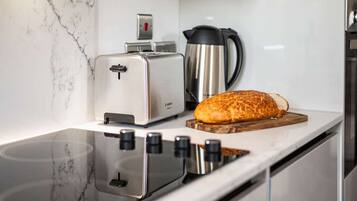 A kitchen with a toaster, a bread loaf on a wooden board, and a coffee maker.