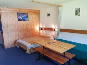 Ein Zimmer mit einem hölzernen Etagenbett, einem Holztisch mit einer Bank und Blick auf eine verschneite Landschaft durch ein Fenster.