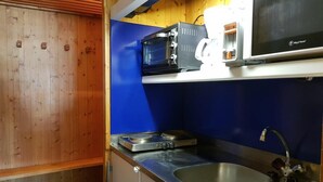 Een kleine keuken met een magnetron, broodrooster en spoelbak.