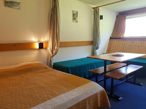 Ein Hotelzimmer mit zwei Betten, einem Tisch und einer Bank.