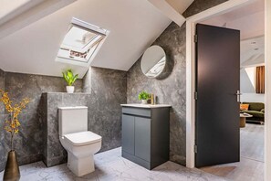 Un baño moderno con inodoro, lavamanos y espejo.