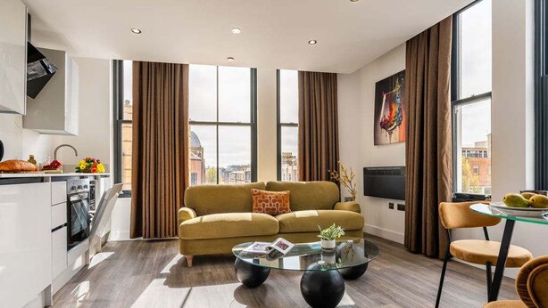 A modern living room with a sofa, coffee table, and dining area.
