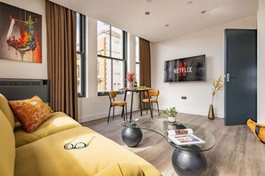 A modern living room with a sofa, coffee table, and a dining area with chairs. - Albemarle Chambers Central Retreat Lift Sleeps 2 (Scarborough)