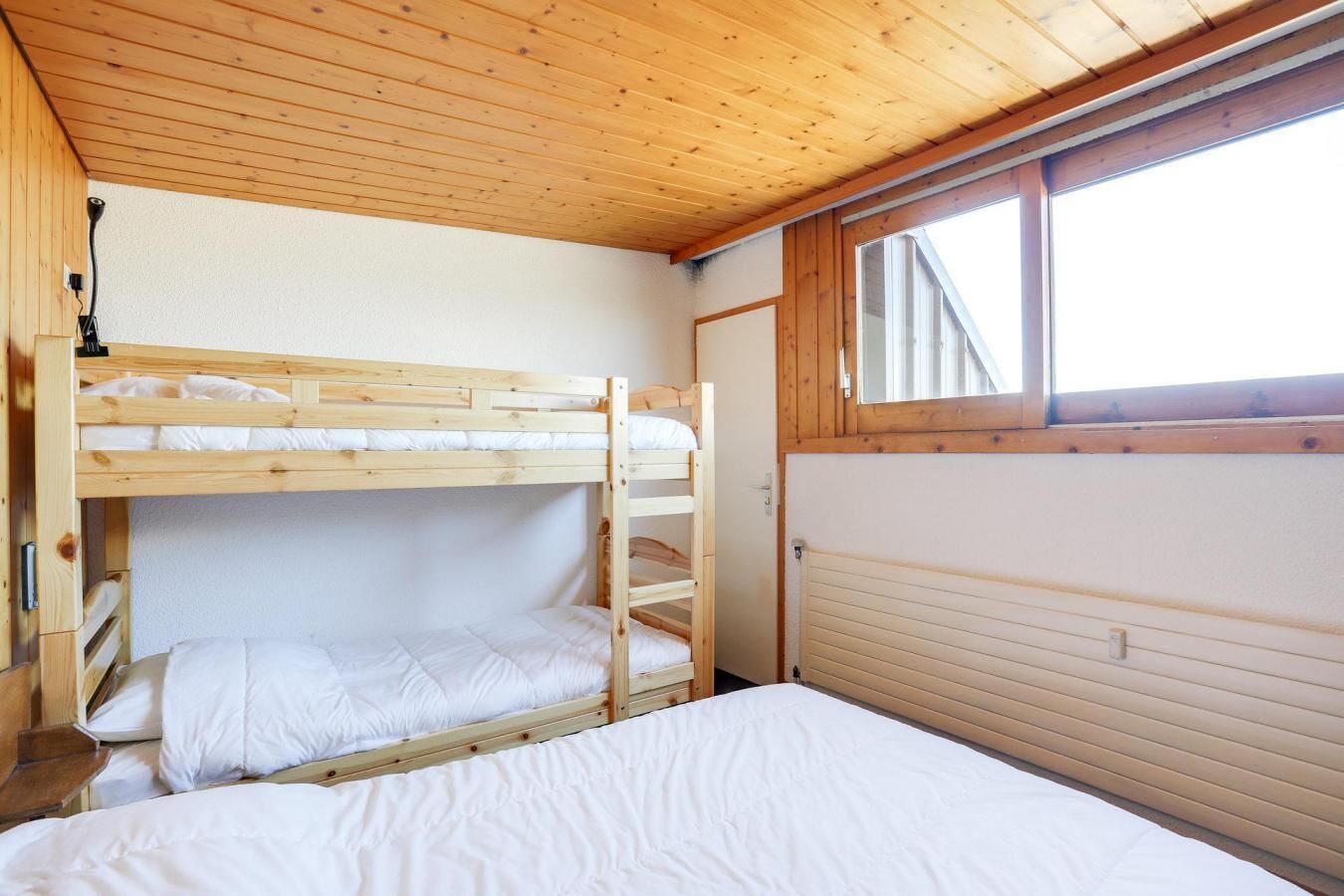 Camera con letto a castello, pareti in legno e una finestra.