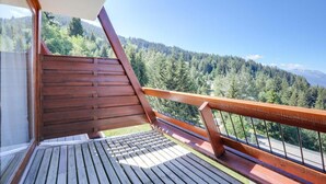 Een houten terras met uitzicht op een bebost berglandschap.