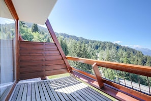 Eine Holzterrasse mit Blick auf einen bewaldeten Bergrücken.