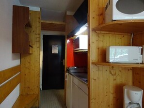 Eine kleine Küche mit Holzausstattung, einer Mikrowelle und einer Kaffeemaschine.