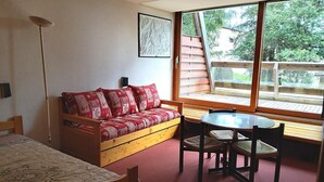 A cozy room with a wooden sofa, a small table, and chairs. There is a window with a view of trees and a wooden deck outside. - 50m from ski slopes, 1st floor, balcony, tv, 30m², Les Arcs (Les Arcs)