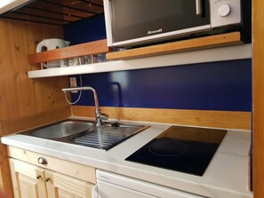 A compact kitchen with a built-in microwave, a sink with a faucet, and a stovetop. - 50m from resort center, 3rd floor, tv, 34m², Les Arcs (Les Arcs)