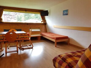 A room with a wooden table, chairs, a bench, a bed, a TV, and a window with curtains. - 50m from resort center, 3rd floor, tv, 34m², Les Arcs (Les Arcs)