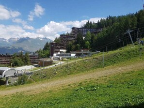 Eine gebirgige Landschaft mit Gebäuden, einer Seilbahn und einer Straße.