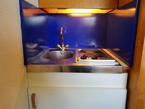 Eine kompakte Küchenzeile mit Spüle, Herd und kleinem Kühlschrank.