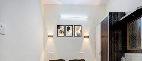 A hotel room with a bed, two wall-mounted lights, and three framed artworks.