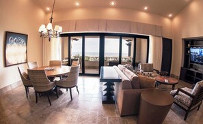 Uma sala de estar ampla, com mesa de jantar, sofá e televisão.