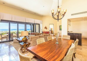 A spacious dining area with a large wooden table, wicker chairs, and a view of the ocean. - 2-bedroom Presidential Condo at the Dunes Club in Diamante Cabo San Lucas (Cabo San Lucas)