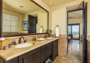 A bathroom with two sinks, a large mirror, and a view of the balcony. - 2-bedroom Presidential Condo at the Dunes Club in Diamante Cabo San Lucas (Cabo San Lucas)