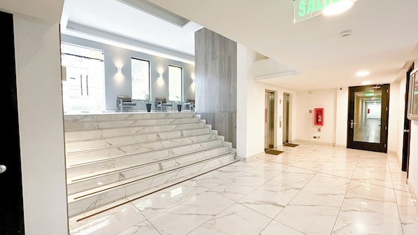 A hotel lobby with marble stairs, a reception desk, and a fire extinguisher. - Modern and comfortable apartment | WIFI | Air conditioning (Santiago)