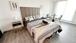 A modern bedroom with a bed, bedside tables, a small desk, and a chair. - Modern and comfortable apartment | WIFI | Air conditioning (Santiago)